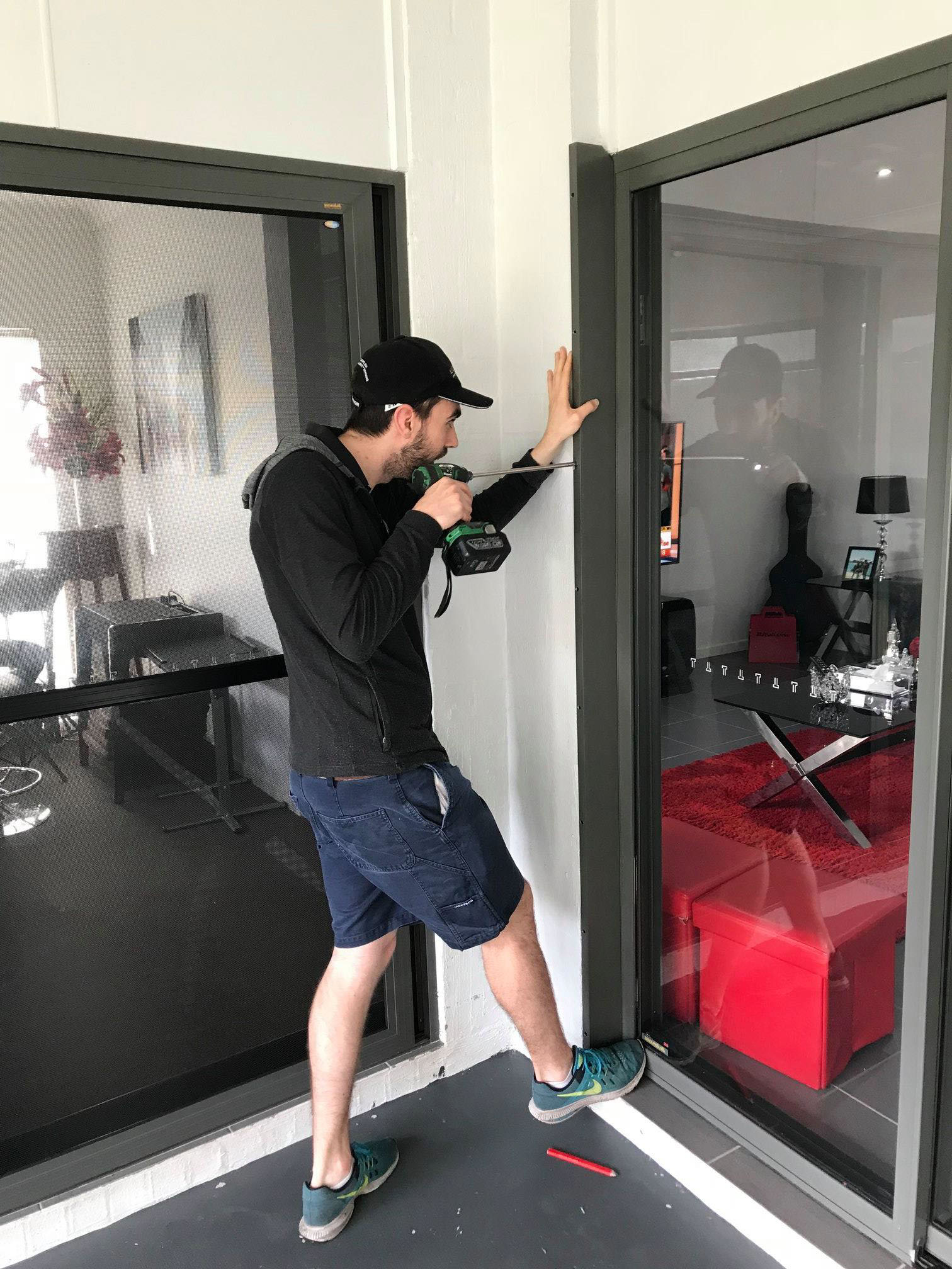 Securelux employed installer fitting a Crimsafe security screen to a door opening